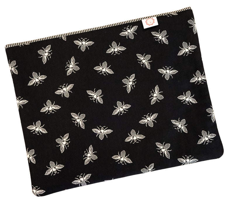 May include: Black fabric laptop sleeve with a white bee pattern.