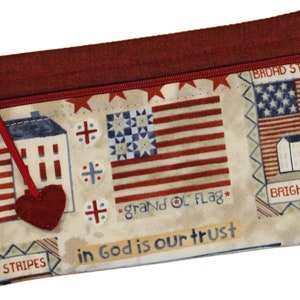 May include: A red, white, and blue fabric zipper pouch with a patriotic theme. The pouch features a small red heart, a house with an American flag, and the text "in God is our trust".