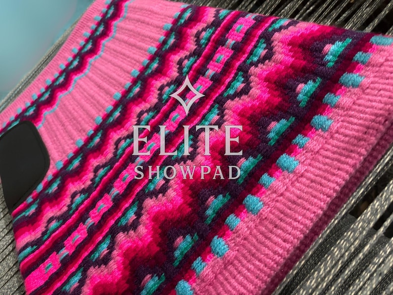 May include: Pink and magenta show pad with a geometric pattern, accented with teal and dark purple. The pad features the text "ELITE SHOWPAD" in white. The pad is designed for equestrian use.