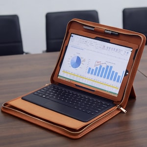 May include: A tan leather tablet case with a zipper closure, containing a tablet with a visible spreadsheet and pie chart on the screen. The case features a built-in black keyboard and a pen holder at the top, providing a structured workspace.