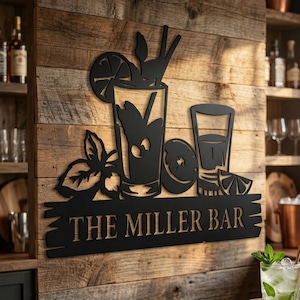 Könnte beinhalten: Schwarze Metall-Wandkunst mit einem Cocktail-Design mit einem Glas, Zitronenscheiben und Blättern. Der Text "THE MILLER BAR" ist auf einem Holzbrett dargestellt. Die Kunst ist an einer Holzwand befestigt.