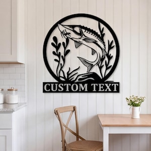 Puede incluir: Un letrero de pared de metal negro con un marco circular que contiene la silueta detallada de un esturión nadando entre plantas acuáticas. Debajo del marco circular hay una placa rectangular con el texto CUSTOM TEXT en negrita.
