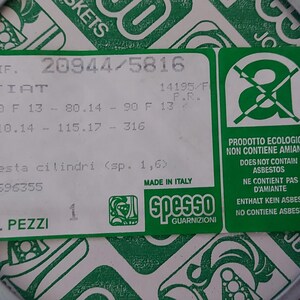 Puede incluir: Una junta gris con anillos de color naranja y una etiqueta verde y blanca. La etiqueta tiene texto que incluye "FIAT" y "MADE IN ITALY". La junta est&aacute; rodeada por un fondo con estampado verde y blanco.