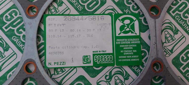 Puede incluir: Una junta gris con anillos de color naranja y una etiqueta verde y blanca. La etiqueta tiene texto que incluye "FIAT" y "MADE IN ITALY". La junta est&aacute; rodeada por un fondo con estampado verde y blanco.