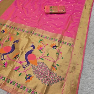 K&ouml;nnte beinhalten: Ein leuchtend rosa Sari mit goldenem Rand und Pfauenmuster. Der Sari hat ein goldenes Feld mit zwei Pfauen, floralen Akzenten und einer rosa Quaste. Ein passendes Stoffst&uuml;ck ist ebenfalls enthalten.