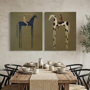 May include: Two framed art prints depicting stylized horses with riders. One horse is dark blue with white star-like patterns, the other is white with black spots. Both have long, thin legs and are set against a muted green background.
