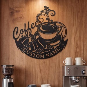 May include: Black metal coffee sign with the word "Coffee" and a coffee cup design. The sign includes the text "CUSTOM NAME". The sign is mounted on a wooden wall, with a coffee grinder, espresso machine, and mugs on a shelf below.