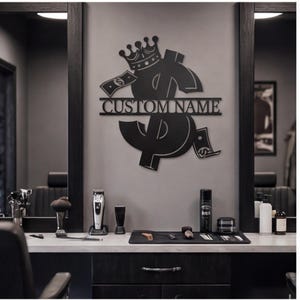 Puede incluir: Un letrero de pared de metal negro con un gran símbolo de dólar coronado y acentuado por dos billetes. Una barra horizontal en el centro contiene el texto CUSTOM NAME en una fuente sans-serif en negrita y en mayúsculas.
