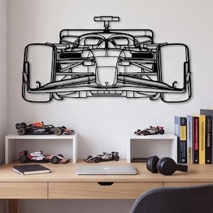 Op de afbeelding: Een zwart metalen wanddecoratie in de vorm van het vooraanzicht van een Formule 1-raceauto. Het ontwerp toont een gedetailleerde omtrek van het chassis, de voorvleugel, de ophangingsonderdelen en de brede banden in een platte silhouetvorm.