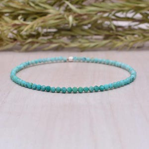 May include: A turquoise beaded bracelet. The bracelet features small, round turquoise beads strung together on a thin cord. The beads are a vibrant turquoise colour, and the bracelet is designed to be worn around the wrist.