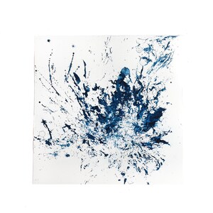 May include: A square piece of white paper featuring a dark blue ink splatter design. The artwork consists of various shades of blue, ranging from deep navy to lighter tones, created through dynamic splashes, drips, and fine droplets of ink.