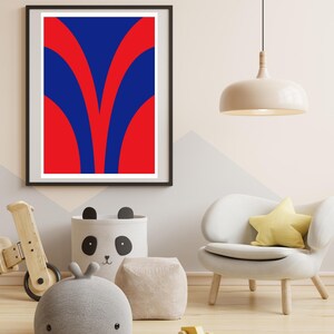 May include: A framed abstract art print with a bold design in red and blue. The artwork features a symmetrical pattern of curved shapes. The print is displayed in a modern interior setting with a white chair and a panda-themed storage bin.