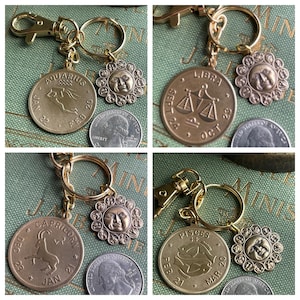 May include: Gold-toned keychains featuring zodiac symbols. Each keychain includes a round charm with a zodiac sign and a smaller sun-faced charm. The signs include Aquarius, Libra, Capricorn, and Pisces. The keychains have a gold clasp and ring.