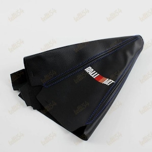 Puede incluir: Fuelle de palanca de cambios de coche de cuero negro con costuras azules. El fuelle presenta el logotipo "RALLI ART" en blanco, rojo y naranja. Diseñado para adaptarse a la palanca de cambios de un coche.