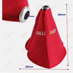 Puede incluir: Fuelle de cambio de marchas rojo con un anillo de metal plateado y el texto "RALLI ART". El fuelle mide 26 cm de ancho y 22 cm de alto. El anillo de metal tiene 7 mm de diámetro.