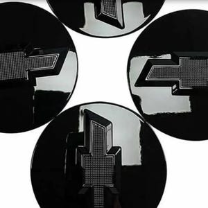 Può includere: Quattro emblemi per auto neri e circolari con un logo Chevrolet argentato. Il logo è una forma a farfalla stilizzata con un centro strutturato e uno sfondo nero lucido. Gli emblemi sono disposti a cerchio.