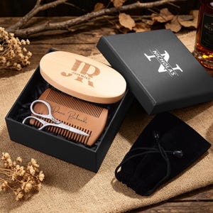 May include: A wooden beard grooming kit in a black gift box. The kit includes a wooden comb, a wooden brush with the initials "JR" and the name "Jeremiah", and a pair of small scissors. The box also contains a black velvet bag.
