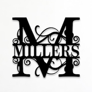 Könnte beinhalten: Ein schwarzes Wandobjekt aus Metall, das einen großen Großbuchstaben M mit dekorativen Schnörkeln zeigt. Der Name MILLERS ist in einem horizontalen Balken in der Mitte des Buchstabens ausgeschnitten. Der Text Custom Order steht oben links.