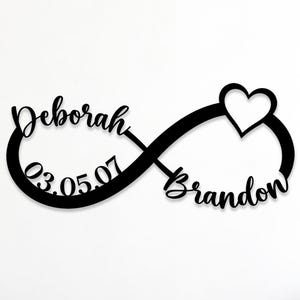 May include: A black wall-mounted sign in the shape of an infinity symbol featuring the names Deborah and Brandon in a cursive script, the date 03.05.07, and a heart icon. The text Custom Order is visible in the upper left corner of the image.