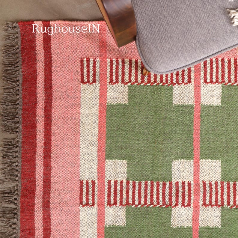 May include: A colorful woven rug with a geometric pattern. The rug features stripes of red, pink, and white, with a green section and white and red block designs. The text "RughouseIN" is visible on the rug.