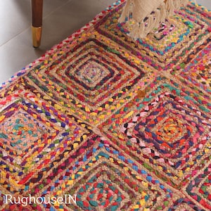 May include: A multi-coloured, hand-woven rug with a diamond pattern. The rug incorporates a variety of colours such as red, yellow, blue, and green. The text "RughouseIN" is visible in the bottom left corner. The rug is made of natural fibres.
