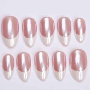 May include: Set of ten oval-shaped, press-on nails. Each nail features a pearlescent pink upper half and a white, curved tip. The nails are arranged in two rows of five against a white background.