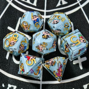 Puede incluir: Un conjunto de siete dados poliédricos con un fondo azul claro y números dorados. Cada dado presenta una ilustración de un personaje de dibujos animados. Los dados están dispuestos sobre una superficie con un patrón en blanco y negro.