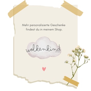May include: A beige paper with the text "Mehr personalisierte Geschenke findest du in meinem Shop." and a cloud graphic with the word "wolkenkind" in cursive. A small pink heart is below the cloud. A sprig of white flowers is taped to the paper.