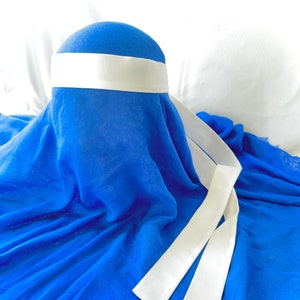 May include: A royal blue fabric head covering with a white satin band and two long white satin ties.