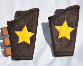 May include: Two brown felt arm bands with yellow star embellishments. The arm bands have brown straps with velcro closures.