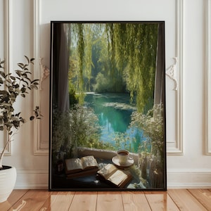 Puede incluir: Una impresión artística enmarcada representa un sereno paisaje acuático visto a través de una ventana. La escena presenta un lago tranquilo rodeado de vegetación, con ramas de sauce llorón enmarcando la vista. Una taza de café y libros abiertos descansan en el alféizar.