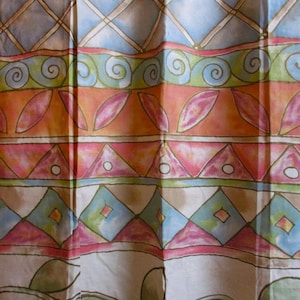 Pode incluir: Um tecido colorido com um padrão repetitivo de formas geométricas e elementos florais. O design apresenta faixas de azul, laranja, rosa e verde, com motivos de diamante, triângulo e espiral. O tecido tem uma aparência macia e fluida.