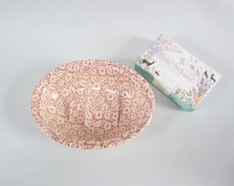 May include: An oval ceramic soap dish with a red and white floral pattern and a rectangular bar of Hand in Hand lavender soap featuring illustrations of deer and floral sprigs on its white and teal paper packaging.