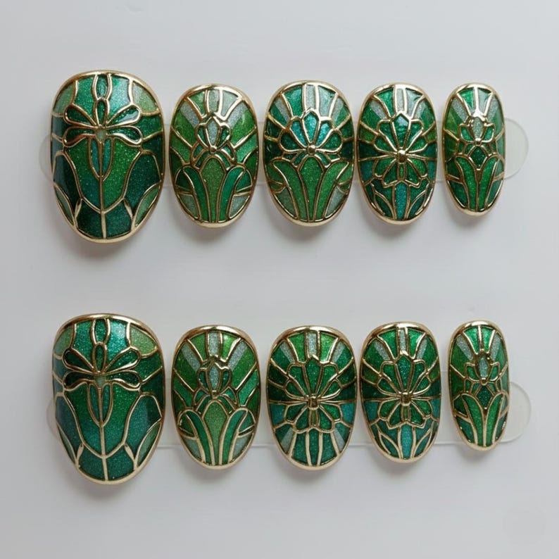 May include: Set of ten oval-shaped, press-on nails. Each nail features a green and gold art deco design. The nails have a glossy finish and are arranged in two rows of five.