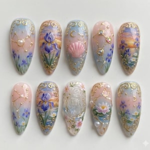 May include: A set of ten almond-shaped artificial nails with intricate hand-painted designs. Each nail features a pastel color palette with floral, celestial, and seashell motifs, accented with gold detailing and small embellishments.