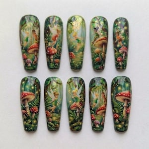 Puede incluir: Conjunto de diez uñas postizas largas y ovaladas. Cada uña presenta una escena detallada de un bosque con hadas, setas y exuberante vegetación. La obra de arte es vibrante con un tema de fantasía, mostrando un diseño caprichoso.
