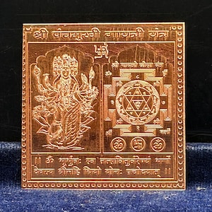 May include: A square copper-colored metal plate featuring an engraved depiction of a multi-headed deity on the left and a geometric yantra pattern on the right. The plate includes Sanskrit text inscriptions and a swastika symbol at the top center.
