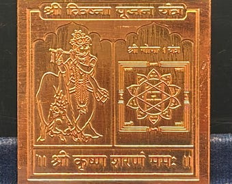 May include: A square copper-colored metal plate featuring an engraved image of Krishna playing a flute next to a cow on the left and a geometric yantra pattern on the right, with Sanskrit text inscribed at the top and bottom borders.