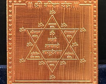 May include: A square copper-colored metal plate featuring an engraved six-pointed star design. The center contains Sanskrit text and Om symbols. The top border displays the text || श्री गीता यंत्र ||. The outer edge is framed by a dotted border.