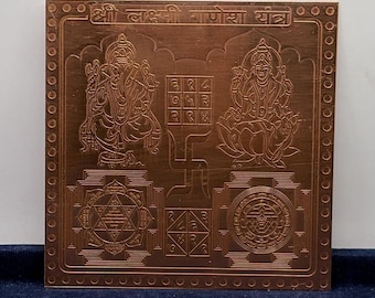 Puede incluir: Una placa metálica cuadrada de color cobre con grabados intrincados de deidades y patrones geométricos. La parte superior incluye texto en devanagari, mientras que el centro muestra una cuadrícula y un símbolo de esvástica.