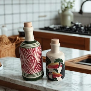 Handmade ceramic olive oil and vinegar bottles with cork stoppers, tropical toucan and palm leaf designs on marble countertop.
Artisan pottery cruet set, hand-painted with red palm leaves and colorful toucans, Mediterranean kitchen decor.
Decorative ceramic oil dispensers, rustic boho style bottles for olive oil, vinegar, or balsamic.
Unique handmade pottery bottles, eco-friendly kitchen gift, perfect for housewarming or gourmet cooking lovers.