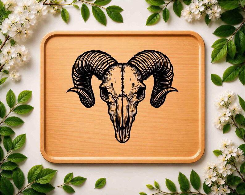 May include: A detailed black and white illustration of a ram skull with large, curved horns. The skull is centered on a light brown wooden tray, surrounded by white flowers and green leaves, creating a natural, decorative theme.