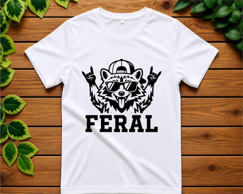 May include: White t-shirt featuring a black graphic of a raccoon wearing sunglasses and a backwards baseball cap, with the word "FERAL" in bold letters below. The raccoon is making a rock and roll hand gesture.