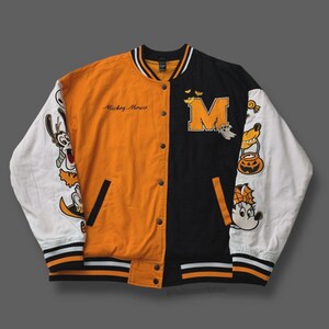 May include: Orange and black varsity jacket featuring Disney characters. The jacket has white sleeves with character patches, a large letter "M", and the words "Mickey Mouse".