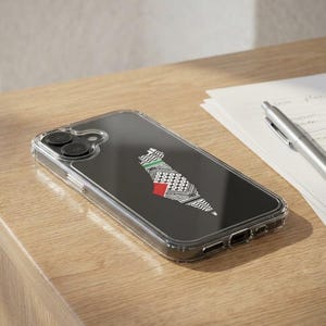 Op de afbeelding: Transparante telefoonhoes met een zwarte achtergrond met een gestileerd kaartontwerp in wit, groen en rood. De hoes ligt op een houten oppervlak, naast een pen en papier.