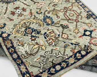 May include: A rectangular area rug with a detailed floral pattern in shades of blue, beige, and pink on a light green background. The rug has a dark blue border with floral accents. The text "TheRugLoom" is visible on the rug.