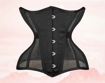 Può includere: Corsetto nero dal design strutturato. Il corsetto presenta un pannello in rete sui lati e un davanti in raso con quattro chiusure color argento. Il capo ha una forma curva ed è progettato per stringere la vita.