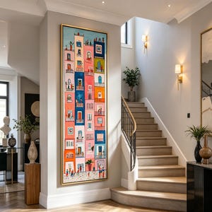 Op de afbeelding: Een groot, rechthoekig, ingelijst schilderij dat een kleurrijke straatsc&egrave;ne met gebouwen uitbeeldt. De gebouwen zijn geschilderd in verschillende kleuren, waaronder roze, blauw, oranje en groen. Mensen worden afgebeeld op balkons en op straat.