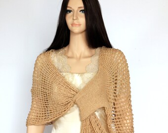 May include: A beige crochet shawl with a delicate openwork pattern. The shawl is draped over a mannequin's shoulders and tied in a knot at the front.