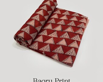 May include: Rolled and flat sections of Bagru Print pure cotton fabric. The fabric features a repeating pattern of cream-colored triangles with black detailing on a deep red background. The text "Bagru Print" and "Pure Cotton Fabric" are visible.
